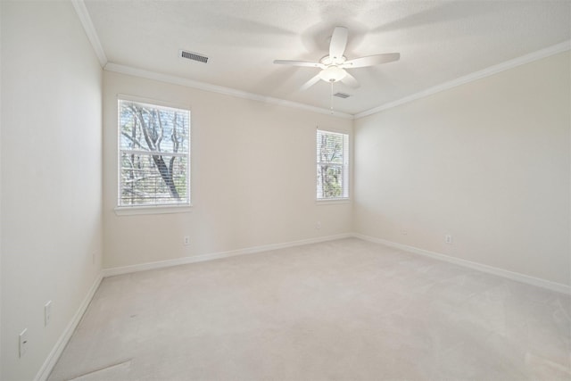 spare room featuring visible vents, ornamental molding, baseboards, light colored carpet, and ceiling fan