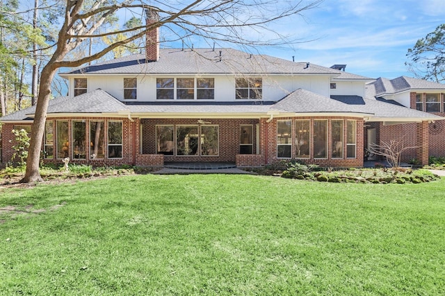 rear view of property with a lawn, brick siding, a sunroom, and a chimney