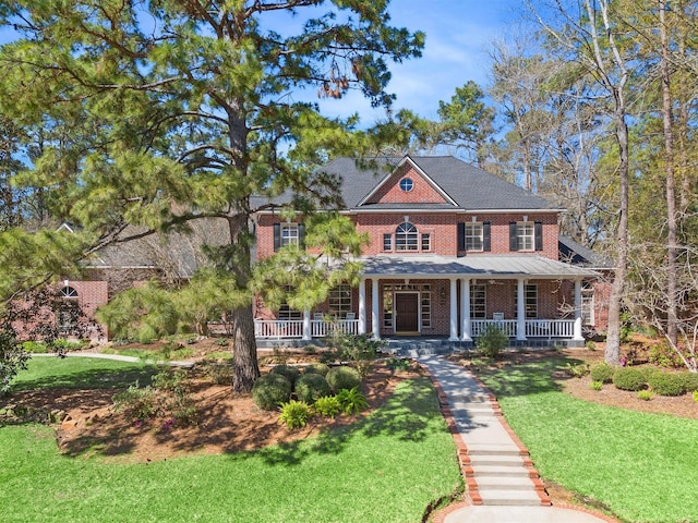 view of front facade with brick siding, covered porch, and a front lawn