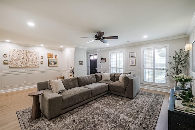 living area featuring a decorative wall, a ceiling fan, and ornamental molding