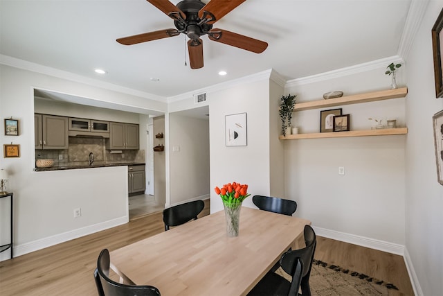 dining space with visible vents, crown molding, baseboards, light wood-style floors, and a ceiling fan