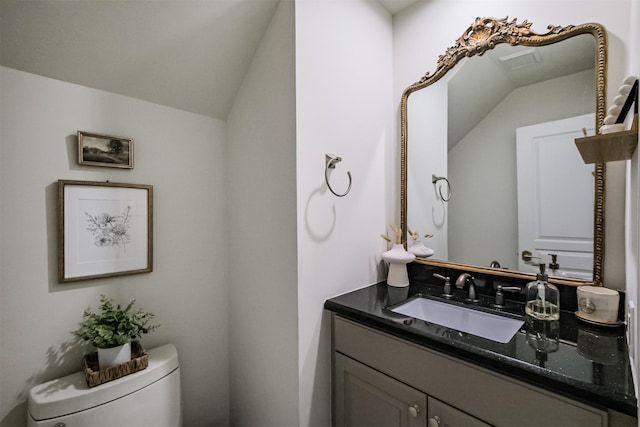 bathroom featuring vanity, vaulted ceiling, and toilet