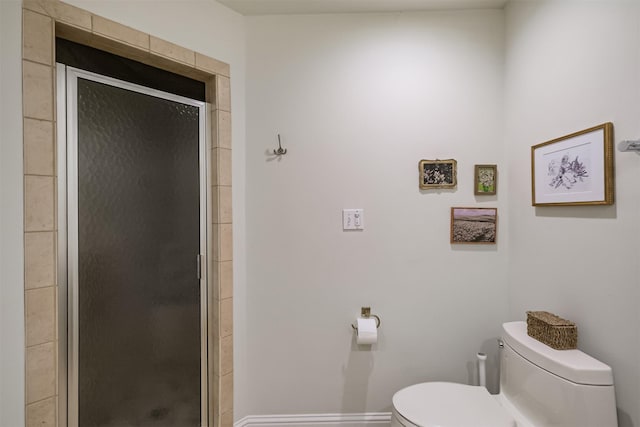 bathroom with a shower stall, toilet, and baseboards