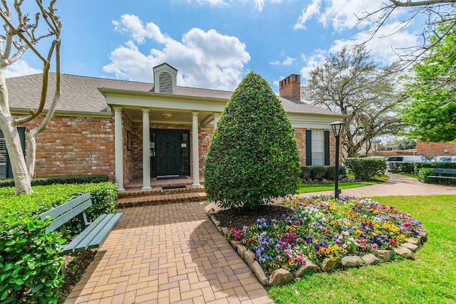 doorway to property featuring a yard and brick siding