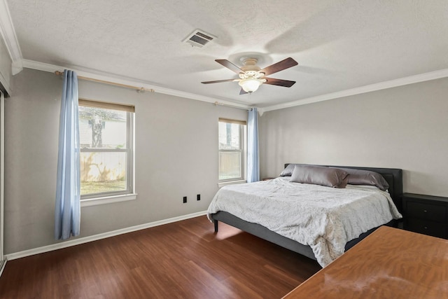 bedroom with visible vents, baseboards, ornamental molding, wood finished floors, and a textured ceiling