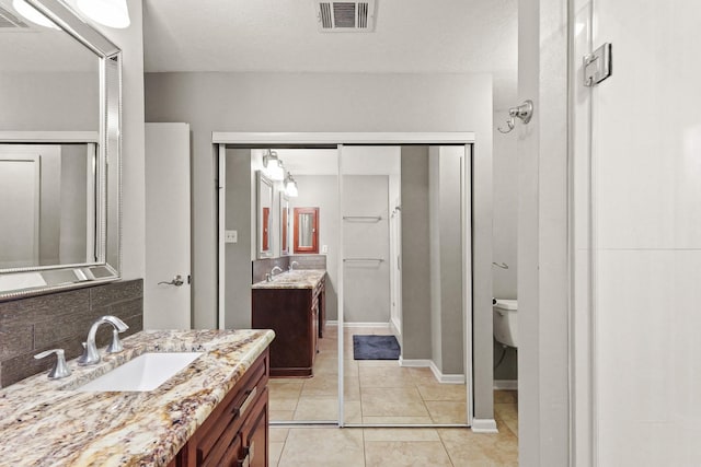 full bath with tile patterned floors, two vanities, visible vents, and a sink