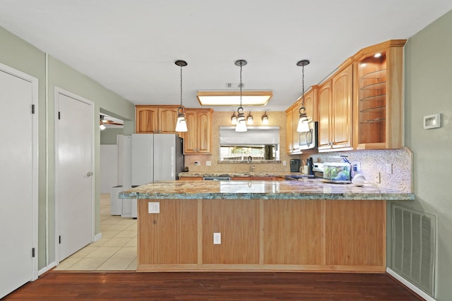 kitchen with visible vents, stainless steel microwave, decorative backsplash, a peninsula, and electric range