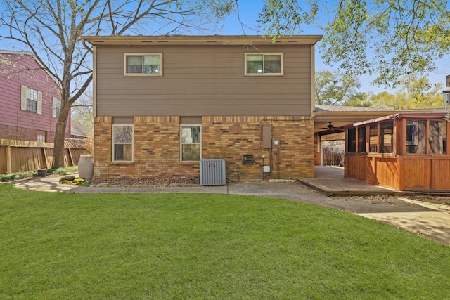 rear view of house featuring brick siding, fence, a lawn, cooling unit, and a deck