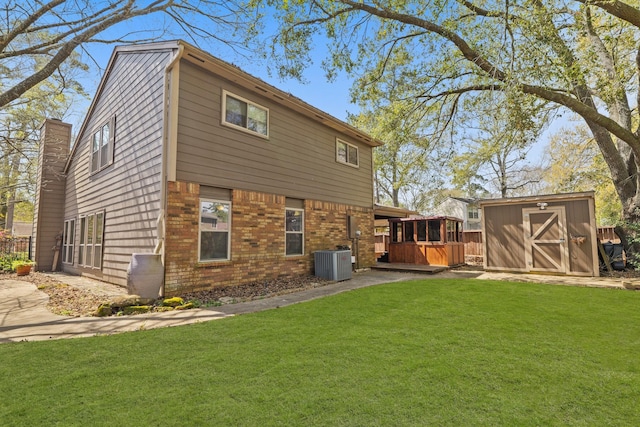 back of house featuring an outbuilding, a yard, central AC, a storage shed, and brick siding