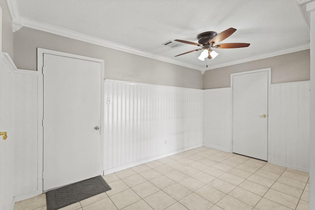 unfurnished room featuring crown molding, visible vents, wainscoting, and ceiling fan