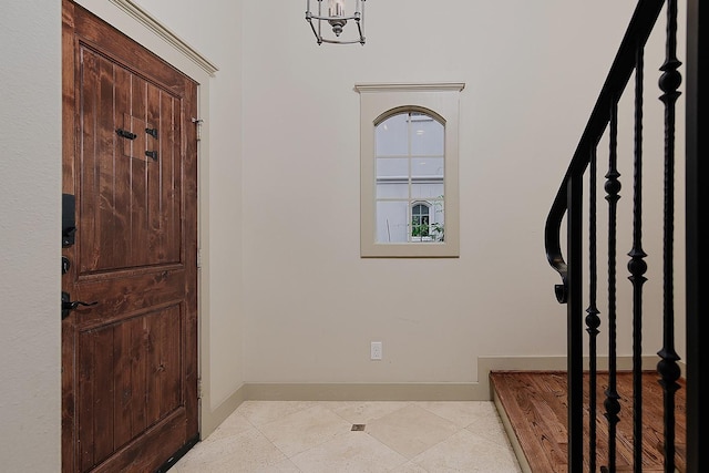 entryway featuring light tile patterned flooring, an inviting chandelier, stairs, and baseboards