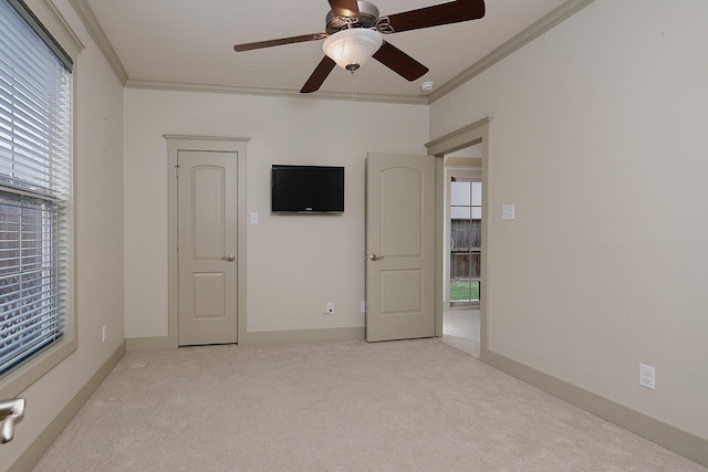 empty room with light carpet, baseboards, crown molding, and a ceiling fan