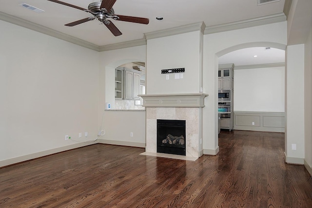 unfurnished living room featuring visible vents, ornamental molding, wood finished floors, arched walkways, and ceiling fan