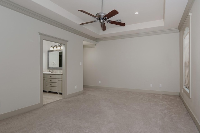 unfurnished bedroom featuring light colored carpet, crown molding, and a raised ceiling