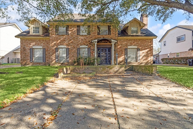 colonial inspired home featuring brick siding, a chimney, and a front yard