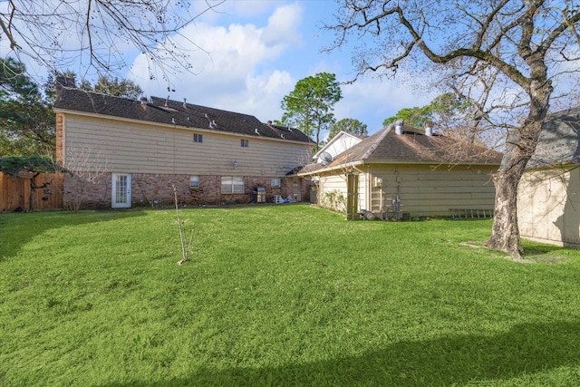 rear view of house with a lawn and fence