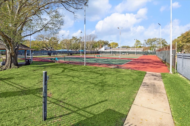 view of home's community with a tennis court, a yard, and fence