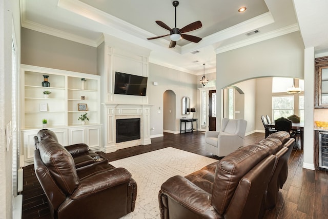 living room featuring a ceiling fan, dark wood-style floors, visible vents, a tray ceiling, and arched walkways