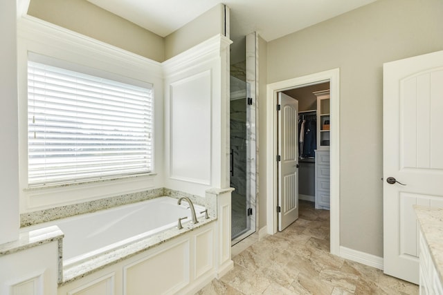 full bath with baseboards, a garden tub, a stall shower, and a spacious closet