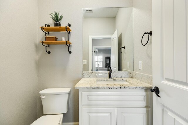 bathroom featuring visible vents, toilet, and vanity