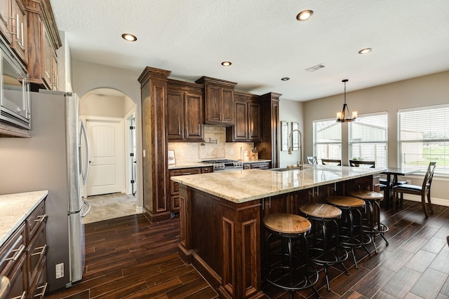 kitchen with a sink, visible vents, arched walkways, and light stone countertops