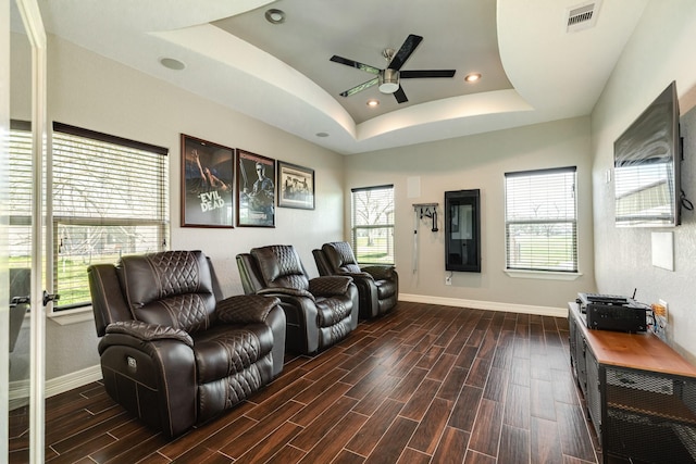 living area with visible vents, wood tiled floor, a tray ceiling, ceiling fan, and a wealth of natural light