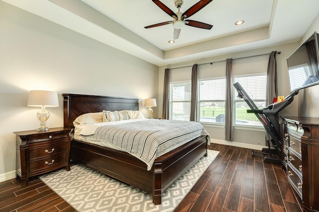 bedroom featuring a raised ceiling, multiple windows, and wood tiled floor