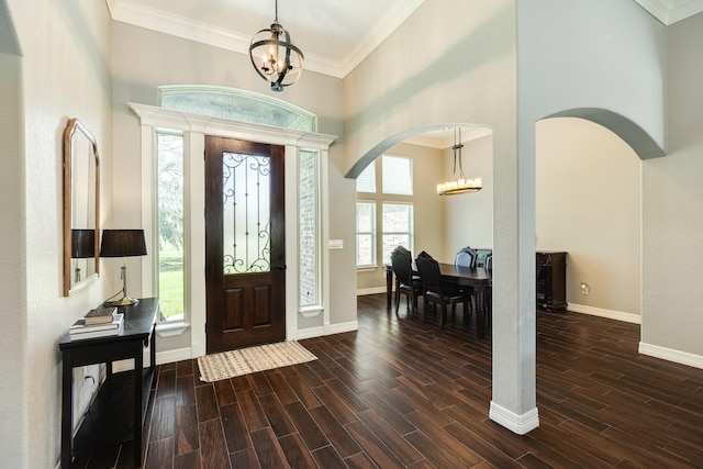 entryway with arched walkways, an inviting chandelier, wood tiled floor, and crown molding