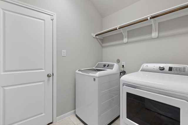 laundry area with light tile patterned floors, baseboards, independent washer and dryer, and laundry area