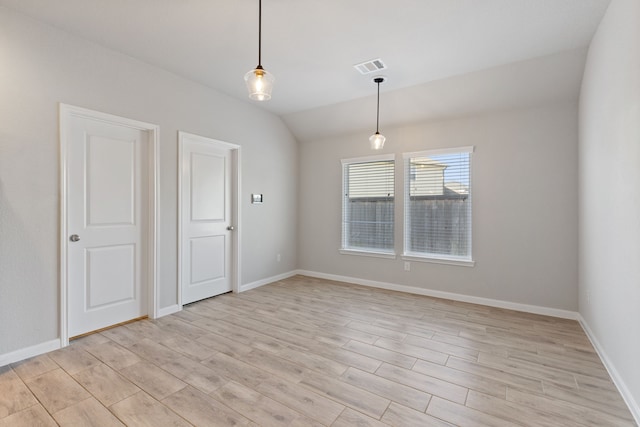 spare room featuring visible vents, baseboards, vaulted ceiling, and light wood finished floors