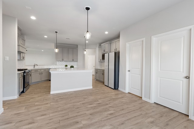 kitchen featuring light countertops, gray cabinets, gas range oven, and freestanding refrigerator