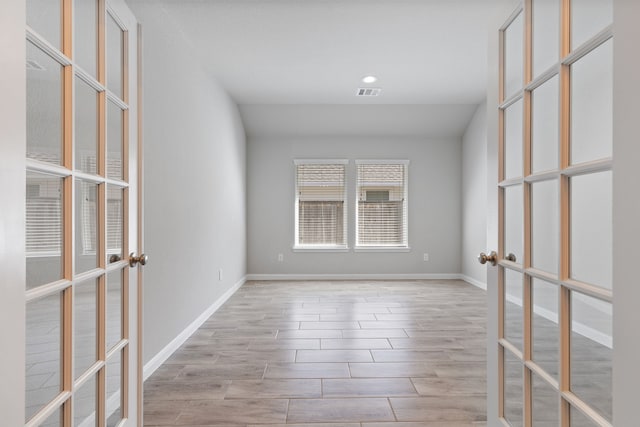 empty room featuring wood finished floors, french doors, visible vents, and baseboards