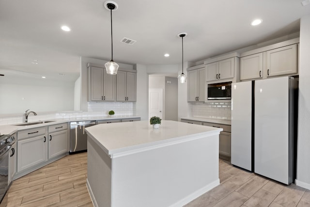 kitchen featuring visible vents, freestanding refrigerator, a sink, black microwave, and stainless steel dishwasher