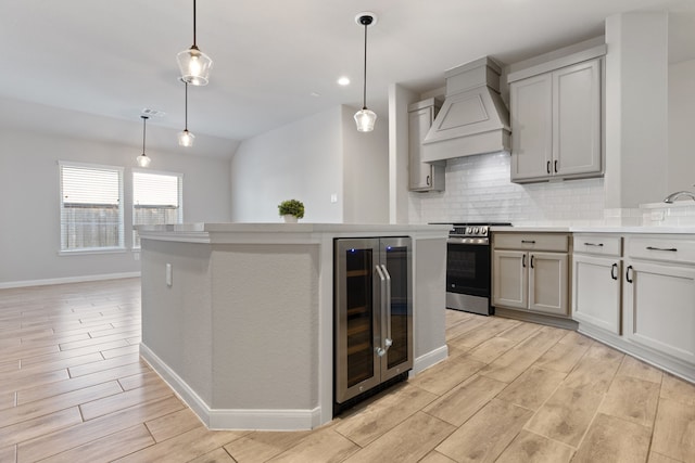 kitchen featuring tasteful backsplash, wood finish floors, wine cooler, stainless steel electric stove, and custom exhaust hood