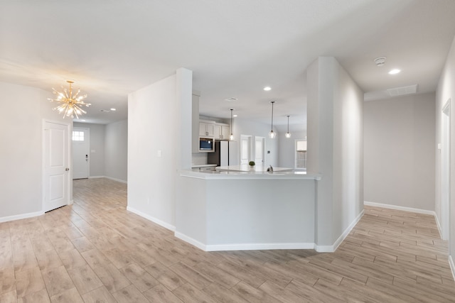 kitchen featuring visible vents, light wood-style flooring, light countertops, white cabinetry, and stainless steel microwave