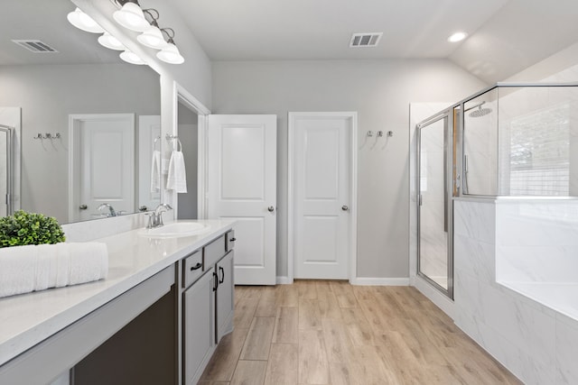 bathroom featuring vanity, wood finished floors, visible vents, and a stall shower