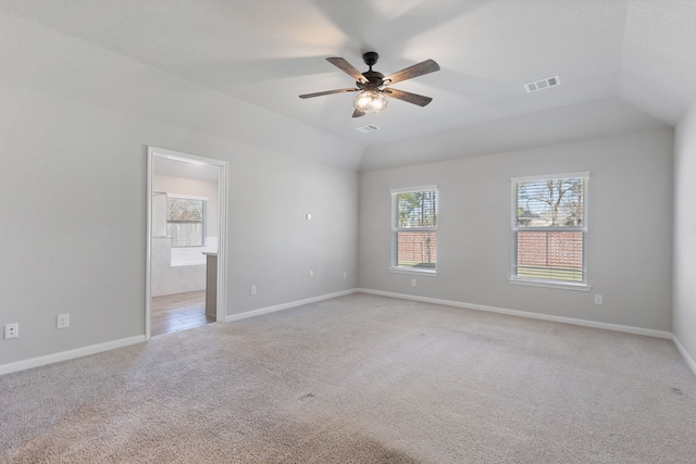 unfurnished room with visible vents, baseboards, lofted ceiling, light carpet, and a ceiling fan