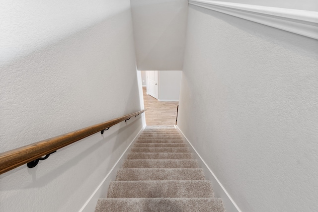 stairway with carpet flooring and a textured wall