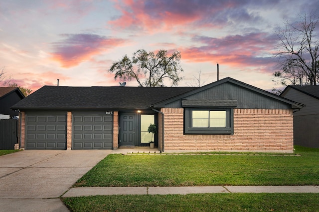 single story home with brick siding, a shingled roof, a front lawn, a garage, and driveway