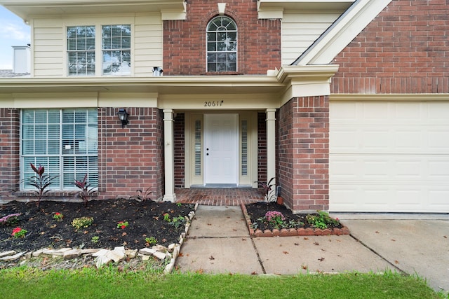 view of exterior entry featuring brick siding and a garage