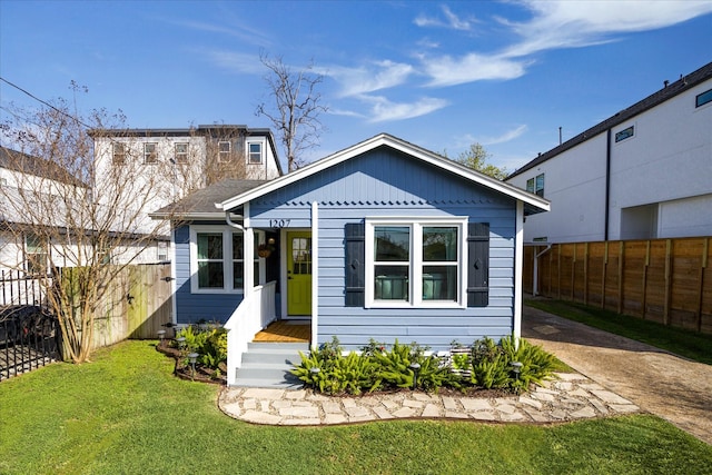 bungalow-style home with a front lawn and fence