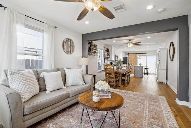 living area featuring visible vents, light wood-style flooring, a ceiling fan, recessed lighting, and baseboards