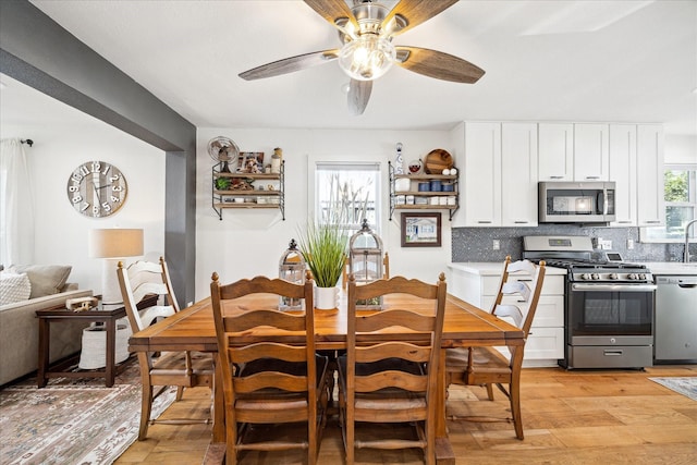 dining space with a ceiling fan and light wood-style floors