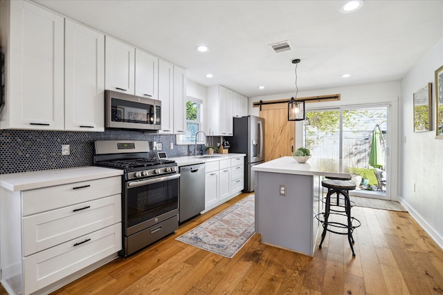 kitchen with light wood-type flooring, a breakfast bar, a sink, tasteful backsplash, and stainless steel appliances