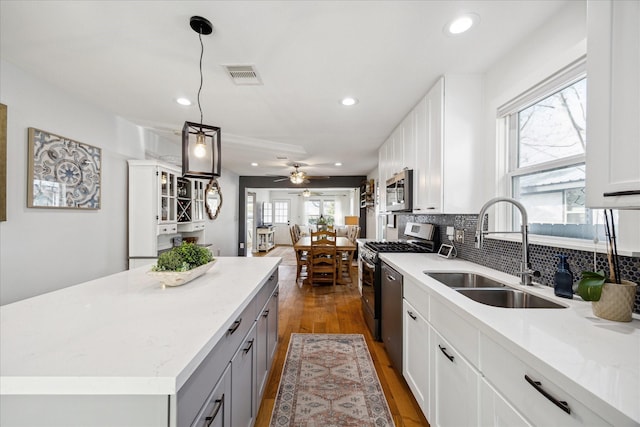 kitchen with visible vents, gray cabinets, a sink, backsplash, and stainless steel appliances