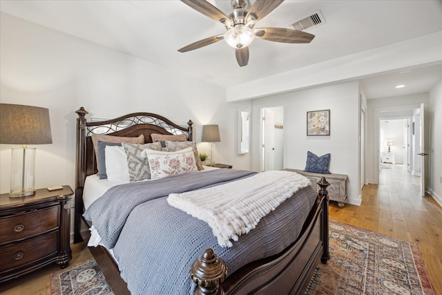 bedroom with light wood finished floors, visible vents, ceiling fan, and baseboards