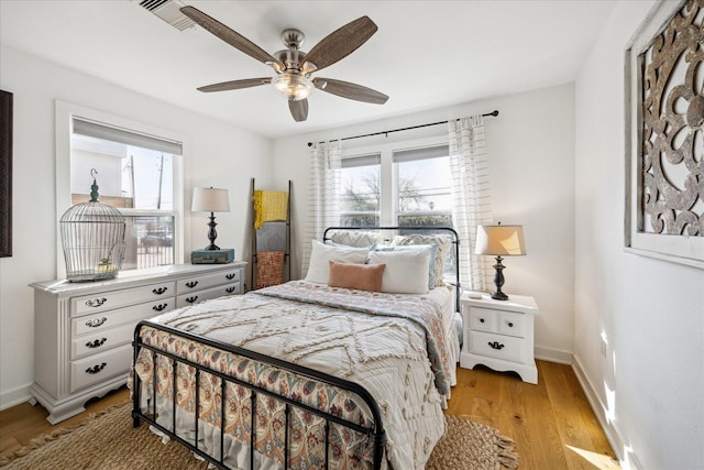 bedroom featuring visible vents, baseboards, a ceiling fan, and light wood finished floors