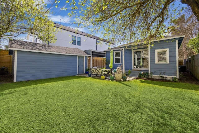 back of house with a lawn, an outdoor structure, and fence