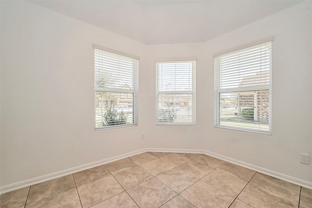 unfurnished room with light tile patterned floors and baseboards