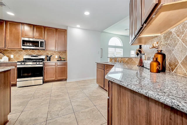 kitchen featuring visible vents, light stone countertops, light tile patterned floors, brown cabinets, and appliances with stainless steel finishes